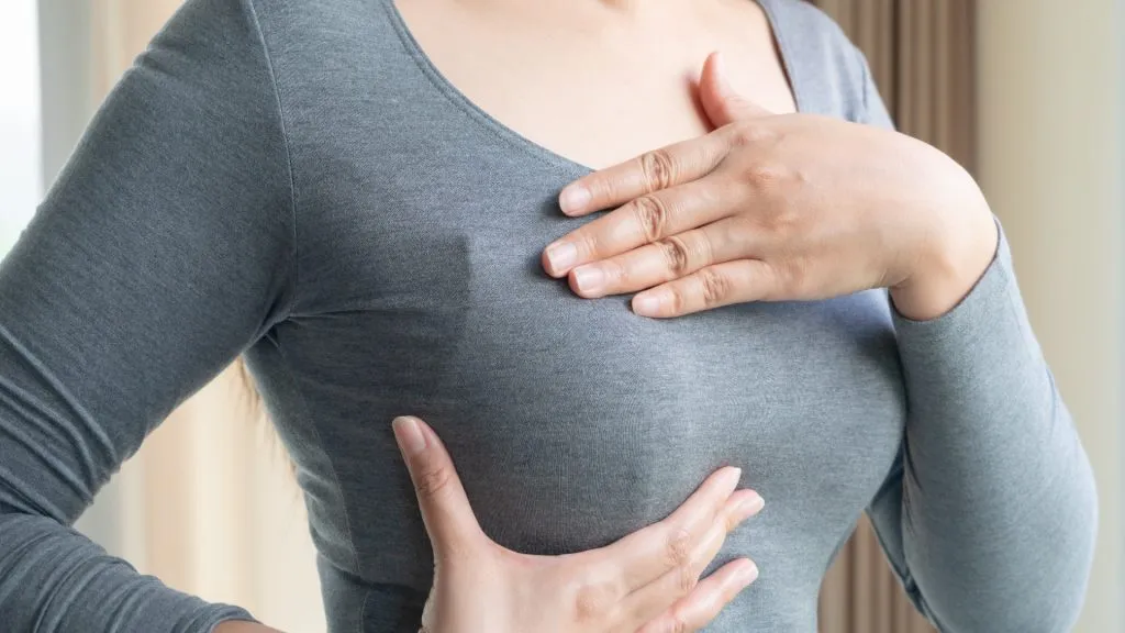 Close up on woman's chest while wearing a gray shirt.