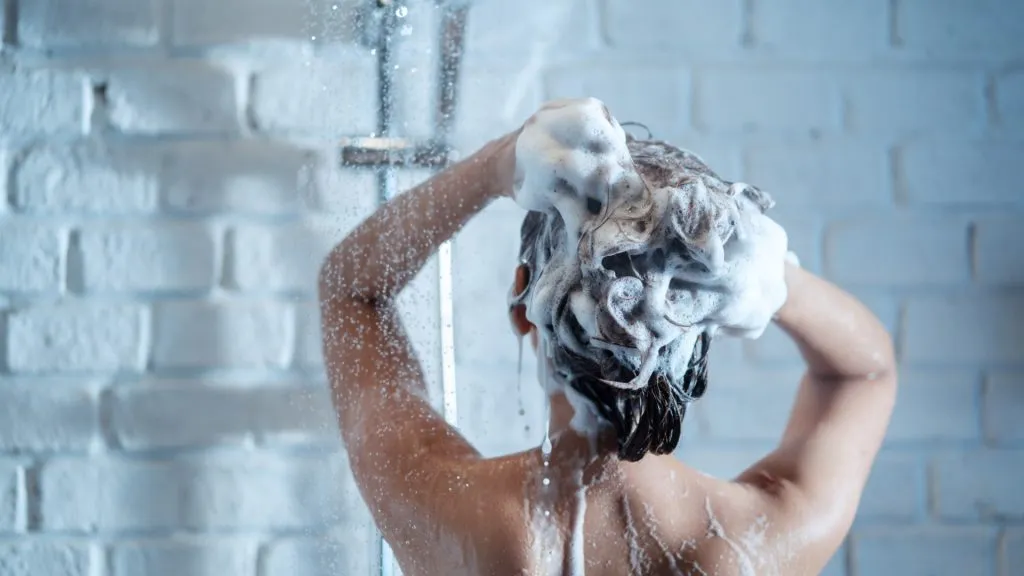 Young beautiful woman taking a shower at home. Female taking care of her hair.