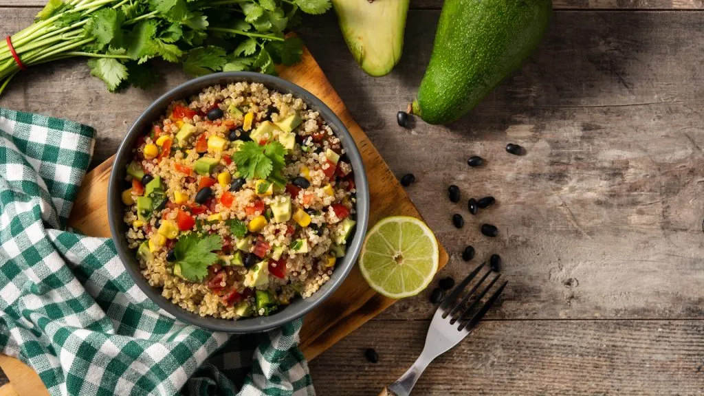 Mexican quinoa salad with avocado and cilantro on wooden background