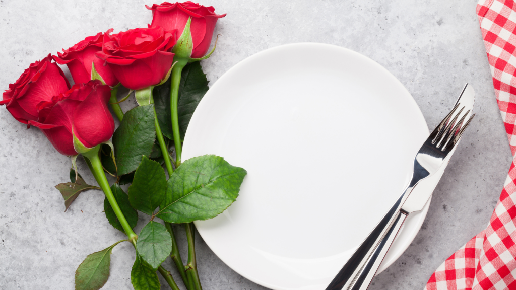 White plate and silverware with red roses nearby