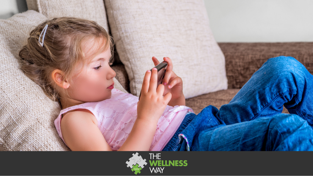 Little girl on couch playing or watching movie on a handheld smartphone