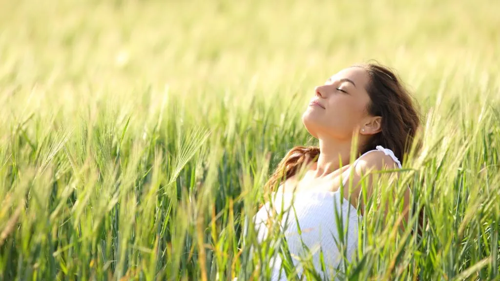 Relaxed woman sitting, stress free, in a field breathing fresh air