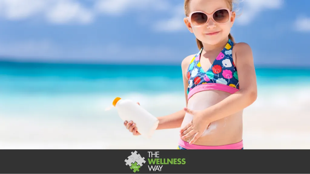 Adorable little girl at tropical beach applying sunblock cream