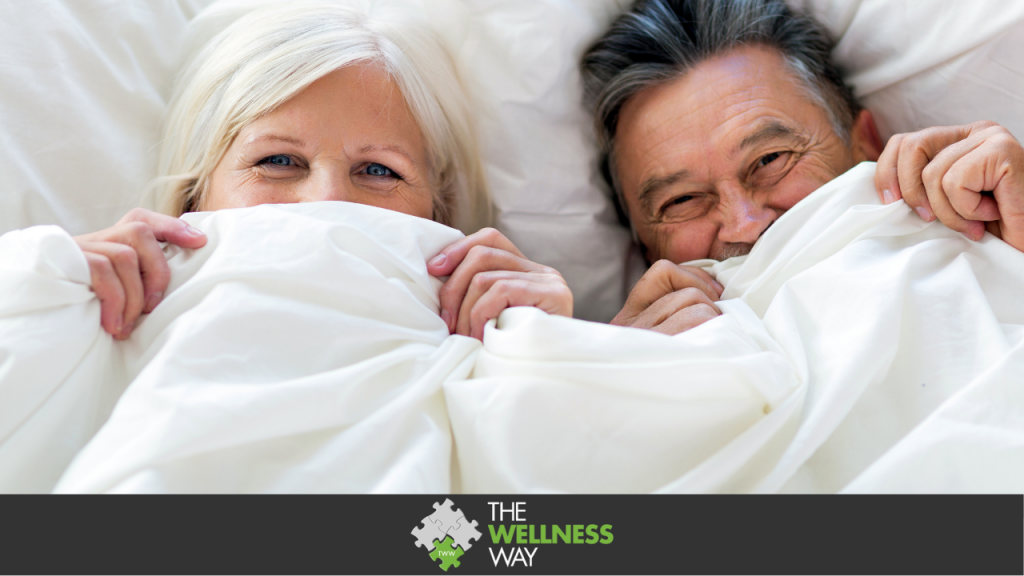 an image of a middle-aged couple with sheets pulled up to their noses. They look happy and smiley after erectile dysfunction!