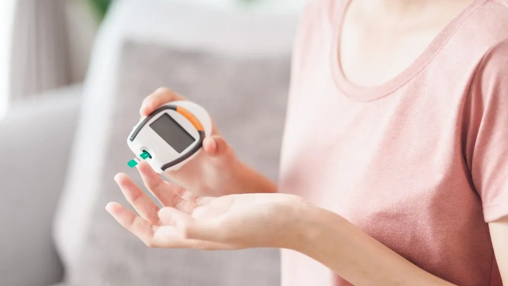 Asian woman checking blood sugar level by Digital Glucose meter