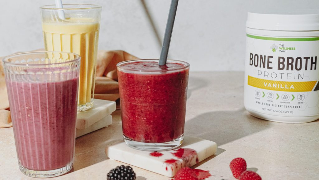 Three kinds of smoothies in glasses with canister of Bone Broth powder on the right.