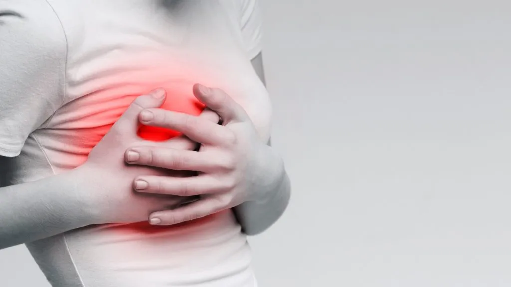 Woman suffering from painful feelings, clutching her breast, monochrome photo with red spot