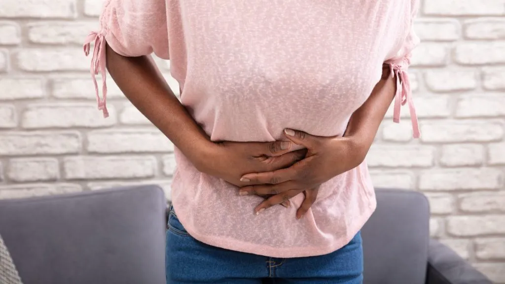 Close-up of black woman suffering from abdominal pain at home