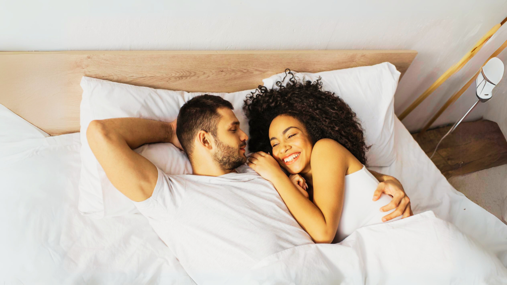 Man and woman lying in bed and happy because they both have a healthy libido and solved their libido problems in the bedroom